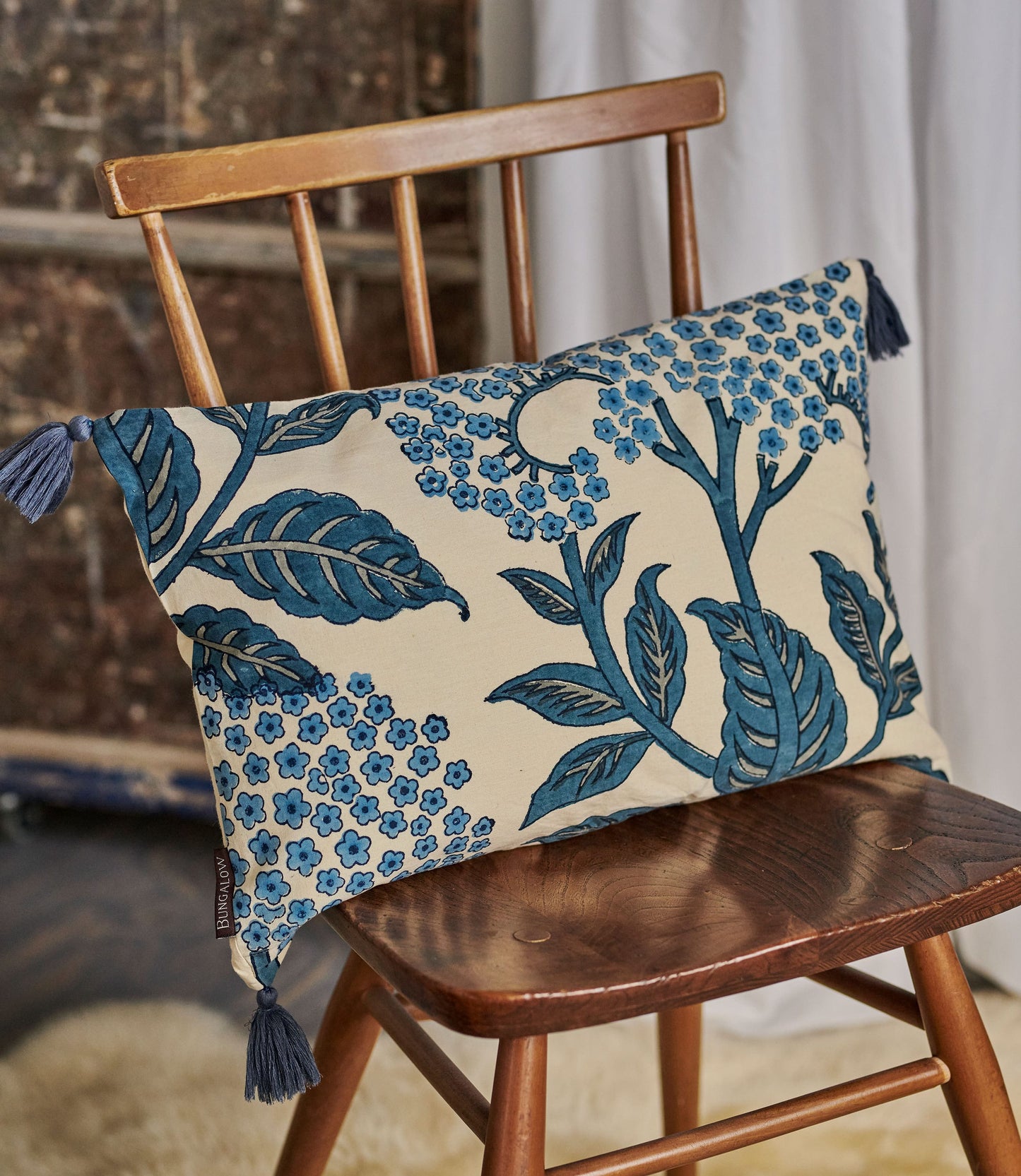 Decorative pillow with blue floral pattern on a wooden chair