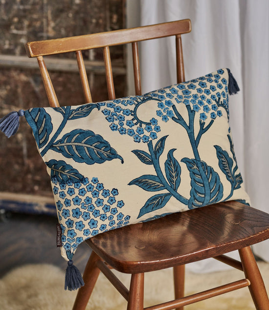Decorative pillow with blue floral pattern on a wooden chair