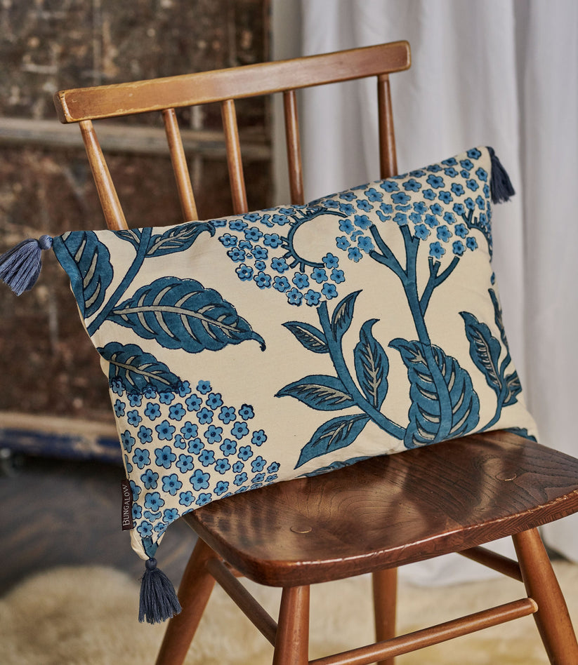 Decorative pillow with blue floral pattern on a wooden chair